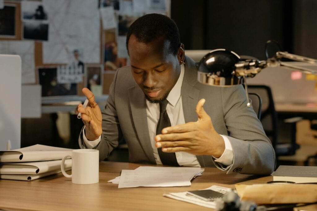 A professional man in a suit applying office-friendly perfume in a modern workspace.