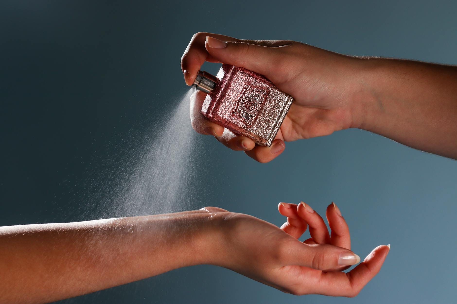 Close-up of a woman applying perfume spray to her wrist, demonstrating proper perfume dosage technique.