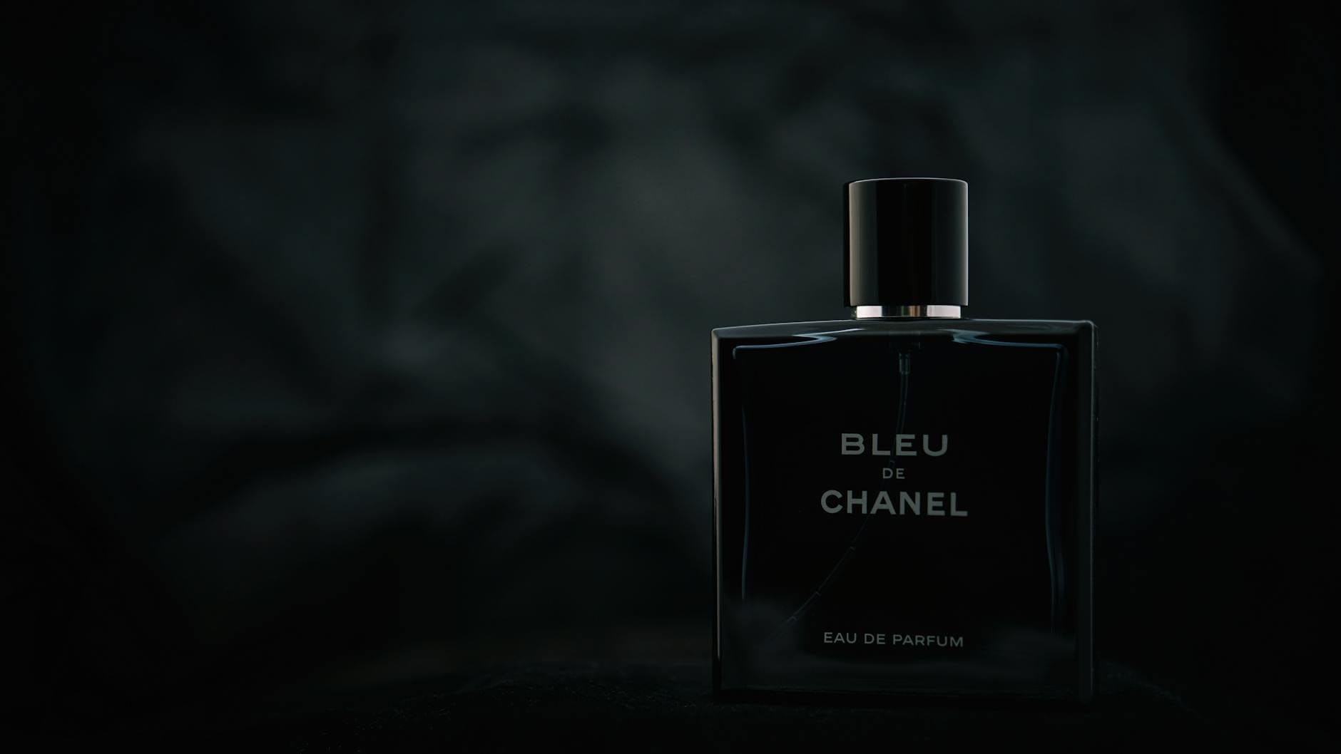 A collection of the best Chanel perfumes for men, including Bleu de Chanel, Allure Homme Sport, and Égoïste, displayed on a dark wooden surface.
