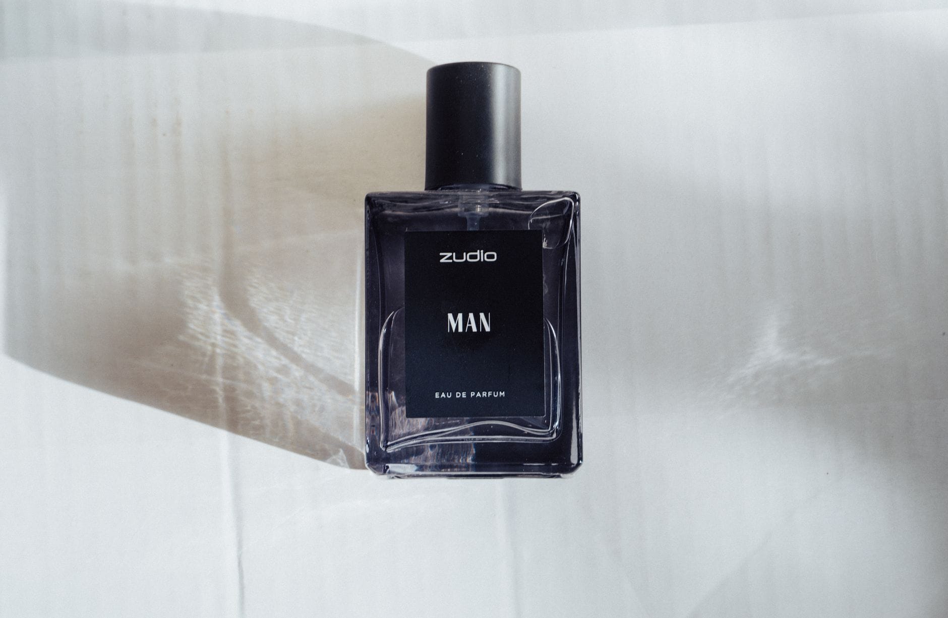 A man applying an affordable Dior Sauvage dupe from a sleek bottle in a modern bathroom setting.