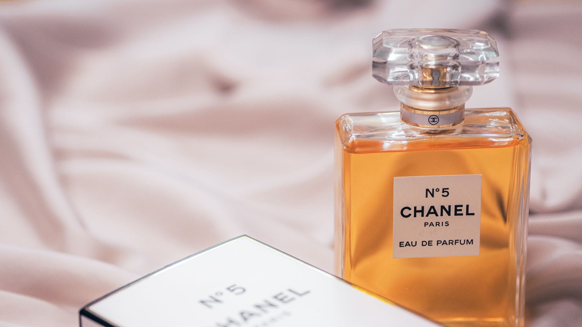 Elegant woman holding a bottle of Chanel perfume in a luxurious setting, representing the best Chanel perfumes for women in 2026.