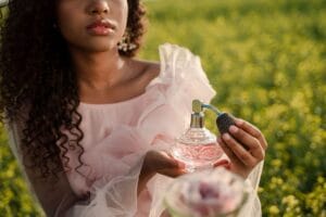 A diverse group of women in spring outfits holding perfume bottles in a garden, representing fresh, floral, and citrus spring fragrances for 2026.