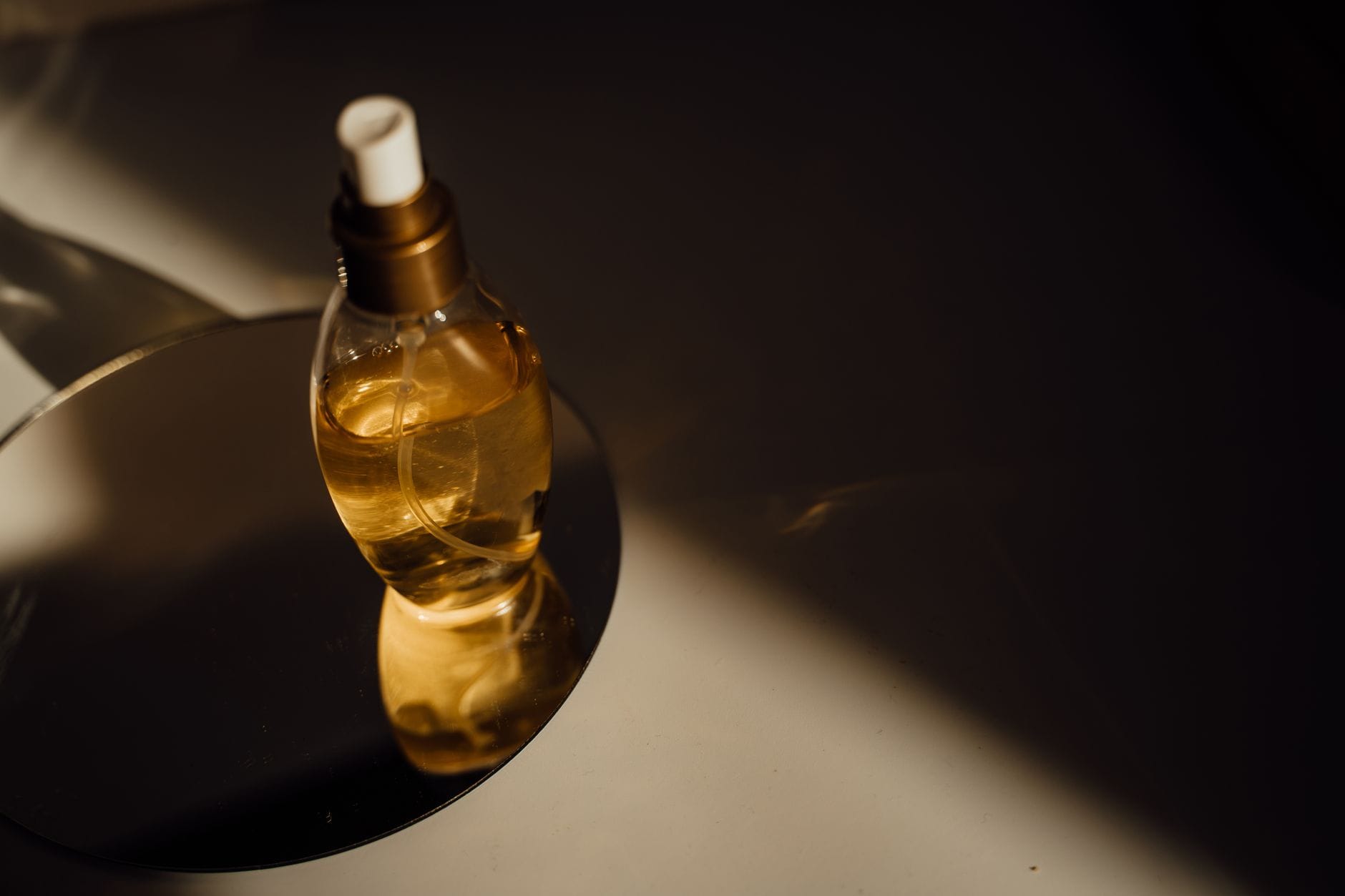 A luxury perfume bottle reflecting on a dark surface under warm, golden light, symbolizing addictive and captivating fragrances.
