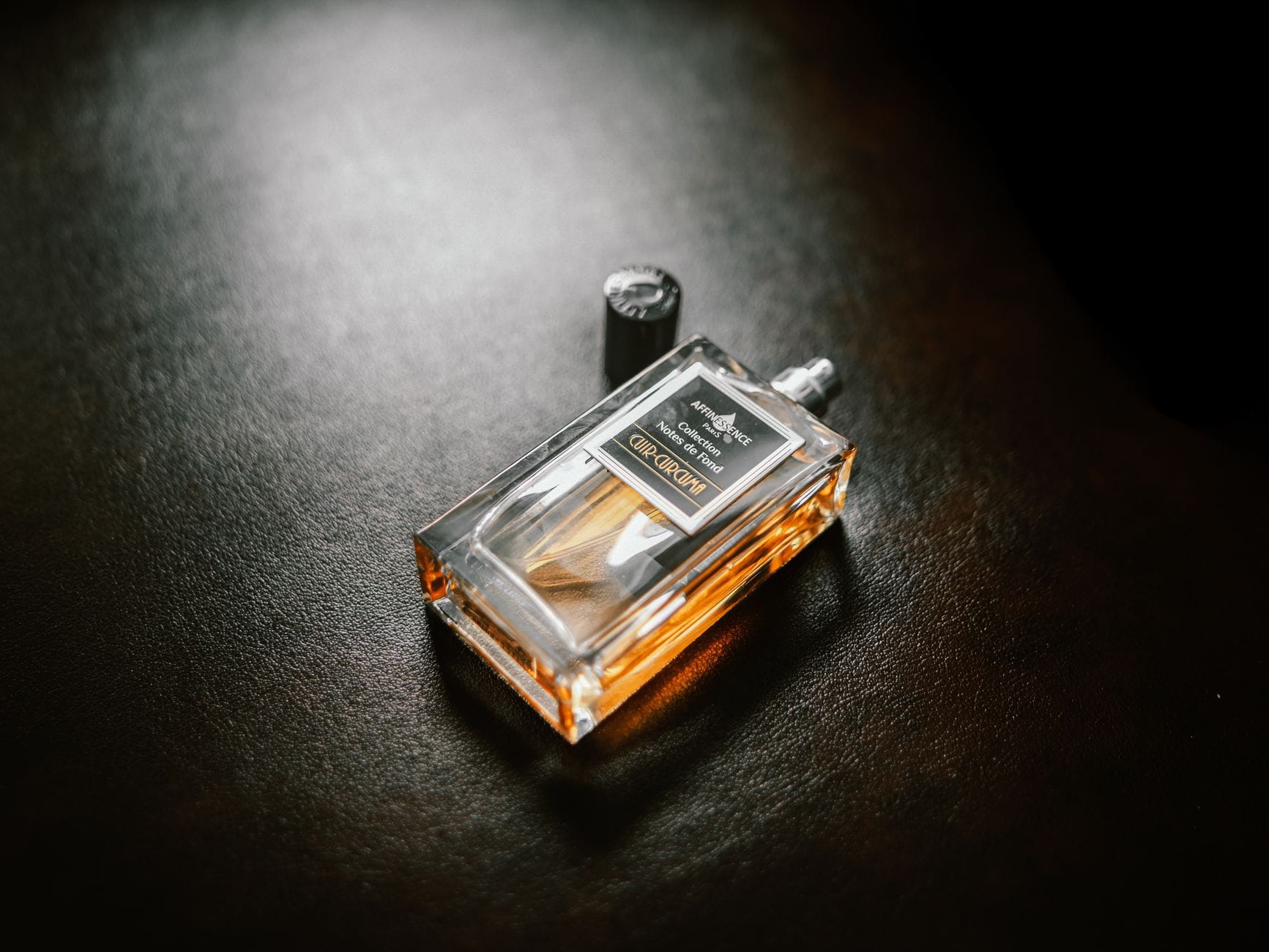 An artistic and unique perfume bottle surrounded by colorful abstract smoke, representing avant-garde fragrances.