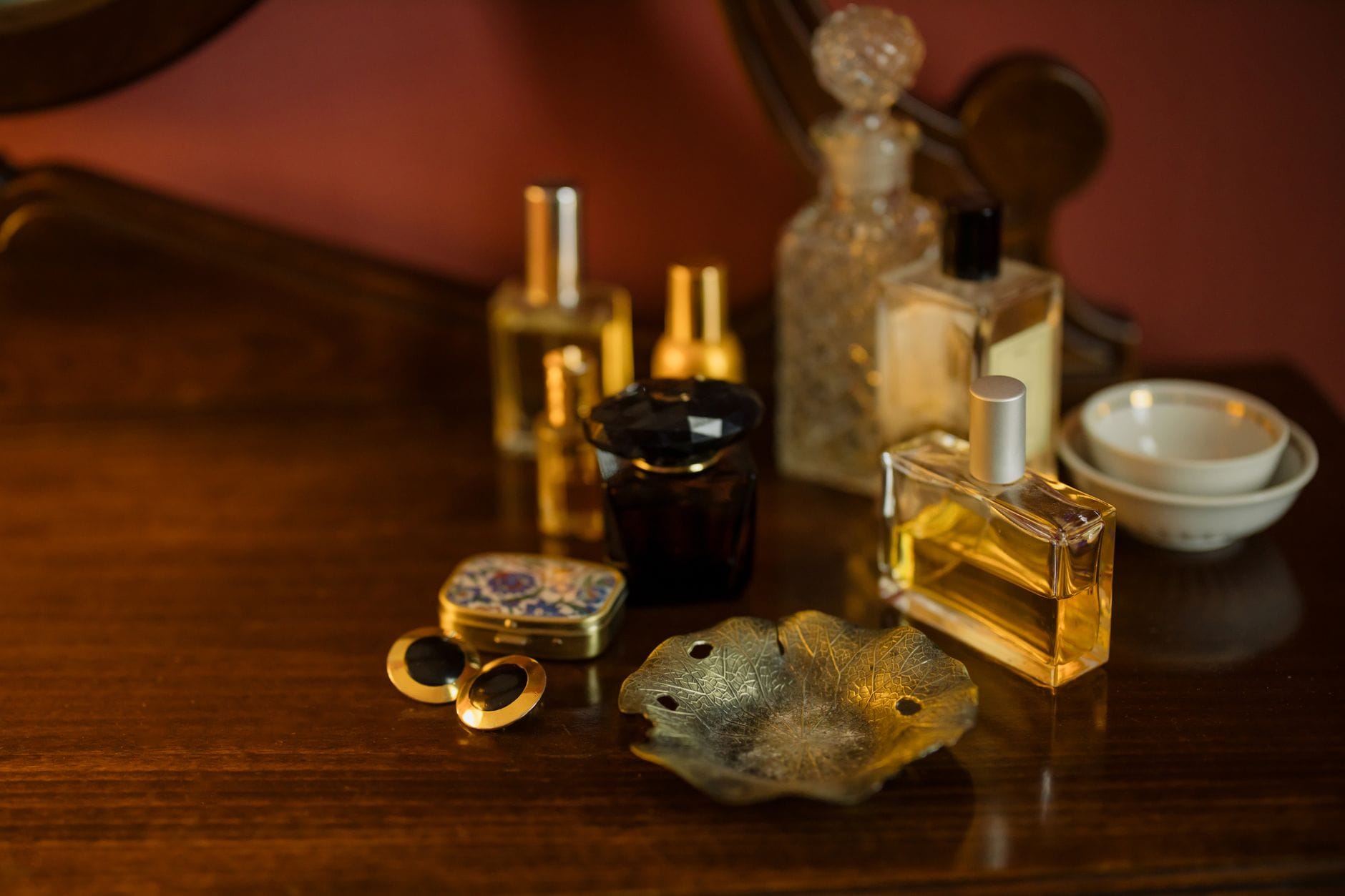 Elegant woman applying a seductive perfume in a modern bathroom with luxury fragrance bottles on the vanity.