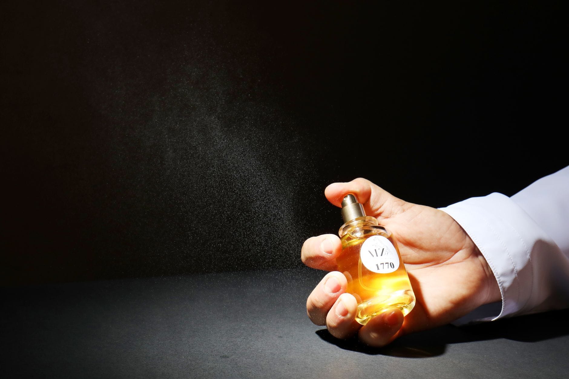 Elegant luxury perfume bottle spraying a fine mist of fragrance, symbolizing instant compliment-getting scents.